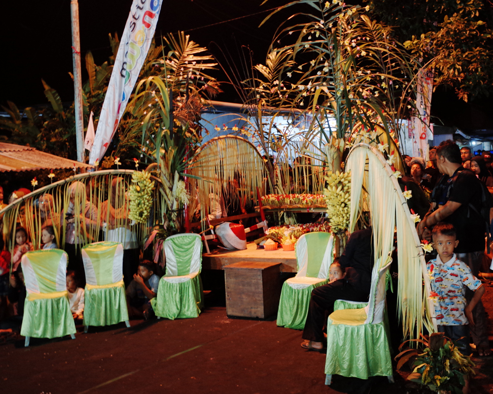 Chairs with decorative green covers on them in front of a table filled with offerings for spirits and flowers for the villagers