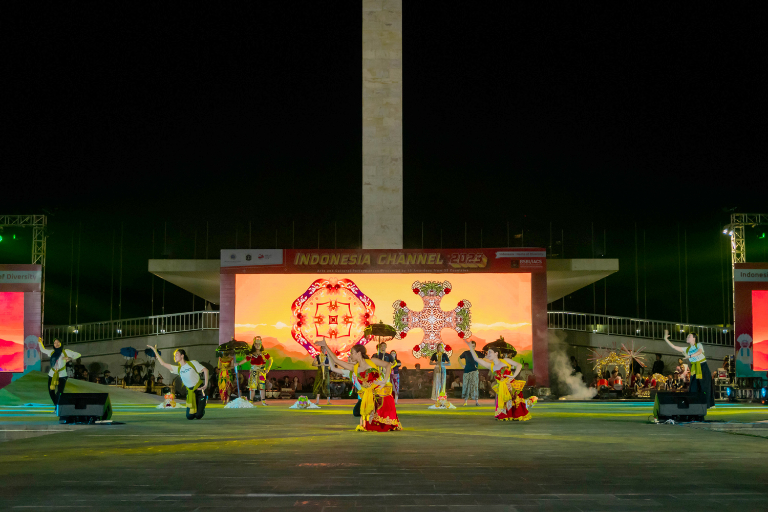 Girls dancing late at night wearing costumes for dress rehearsal in front of the Lapangan Banteng statue